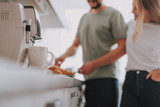 Blurred portrait of man cooking breakfast for his woman. Focus on coffee mug with coffee maker