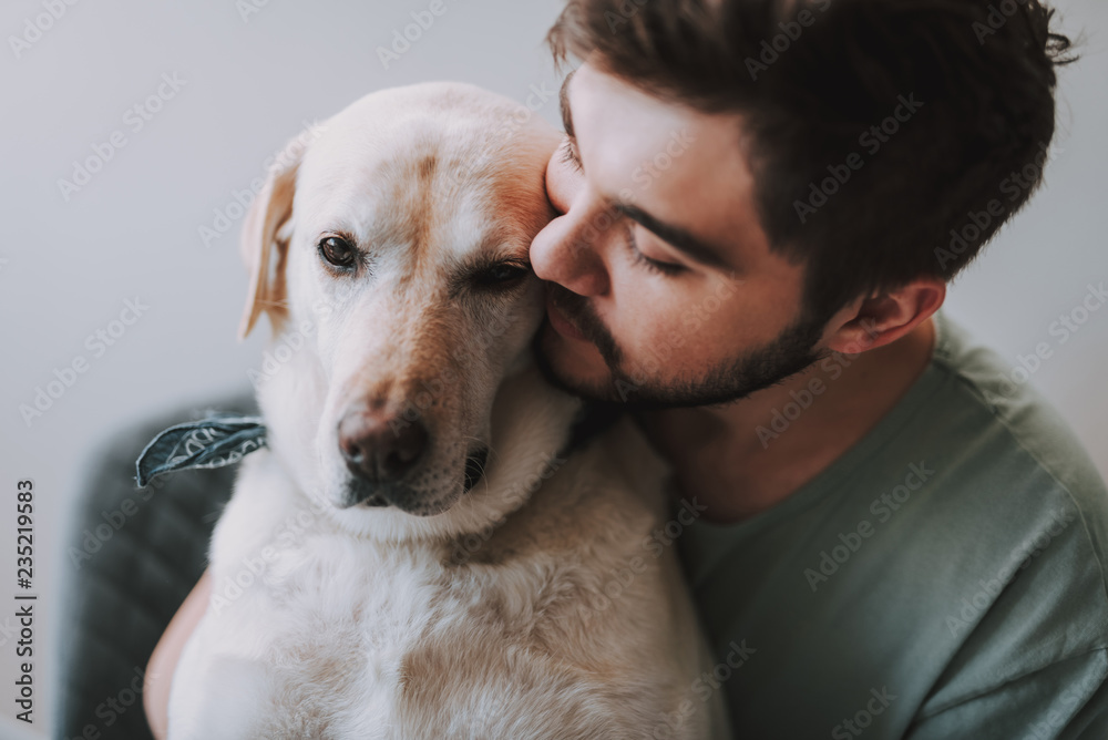 Close up of a bearded man kissing his dog while enjoying rest together - obrazy, fototapety, plakaty 