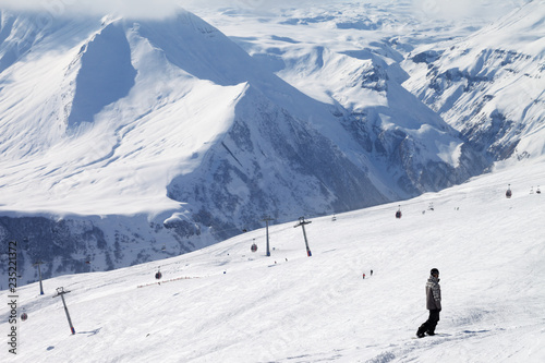 Snowboarder descend on snowy ski slope and gondola lift