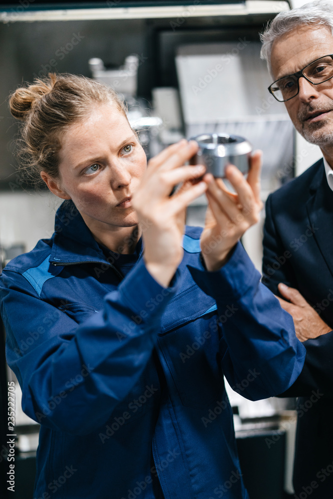 Manager and skilled worker in high tech enterprise, checking machine parts Manager and skilled worker in high tech enterprise, checking machine parts