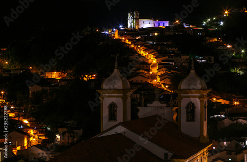 Torres da Igreja de Nossa Senhora da Conceição, em primeiro plano, e Igreja de Santa Ifigênia e casario alinhados ladeira abaixo, ao fundo, em Ouro Preto, Brasil