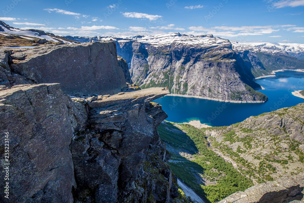Obraz premium Young woman looking carefully over the edge of Trolltunga in Norway