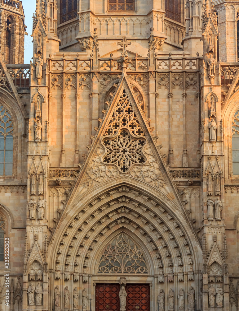 Gothic detail of the facade and tracery by the main front gate of Cathedral of the Holy Cross and Saint Eulalia, or Barcelona Cathedral at sunset in Barcelona, Spain