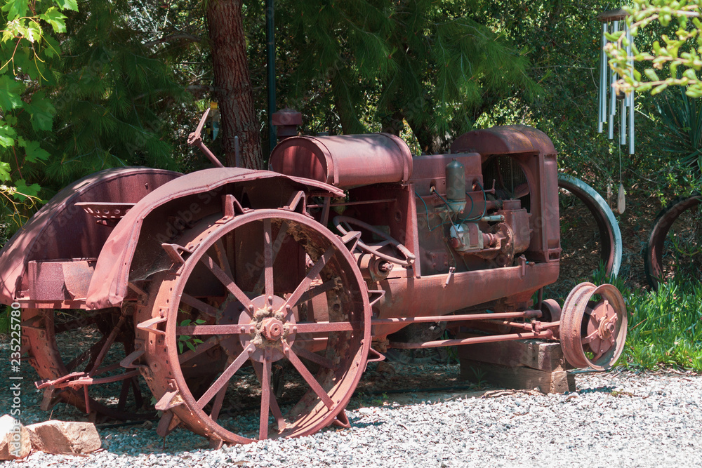 antique depression era steel wheel tractor retired under a shade tree on a farm