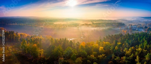 Aerial landscape with foggy sunrise over meadows and forest