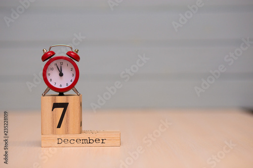 Foto December 7th set on wooden calendar and red alarm clock with blue background