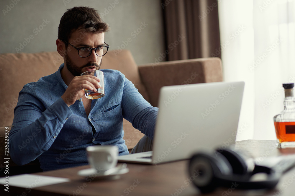 Young man works for a computer from a home with a laptop as a freelancer. Young man works for a computer from a home with a laptop as a freelancer.