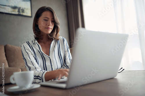 Working home concept – woman works for a computer from a home with a laptop   as a freelancer. photo