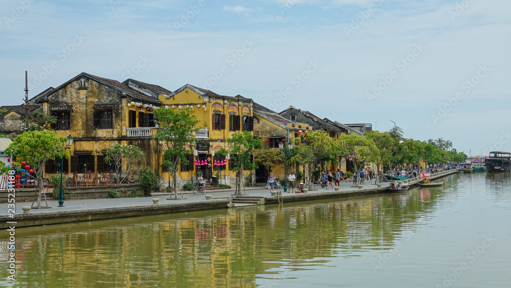 AERIAL: Flying towards an idyllic riverside avenue in a tranquil Vietnamese town
