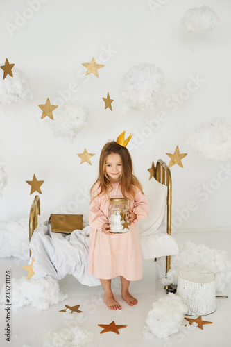 Little princess with a magic wand on а bed in a cloud on a white background