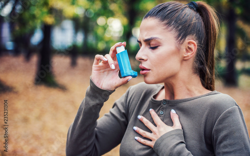 Young woman treating asthma with inhaler photo