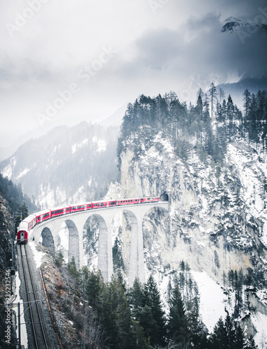 Train crossing canyon by bridge in winter