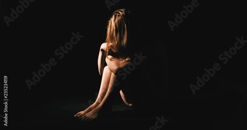 Nude woman in dark room. Abuse and depression concept.