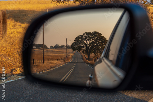 Looking in a rear view mirror while driving down a country road.