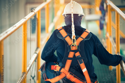 Construction worker wearing safety harness and safety line working at high place