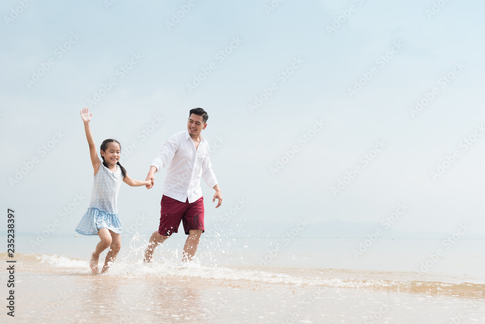 Happy family on beach run and jump at sunset