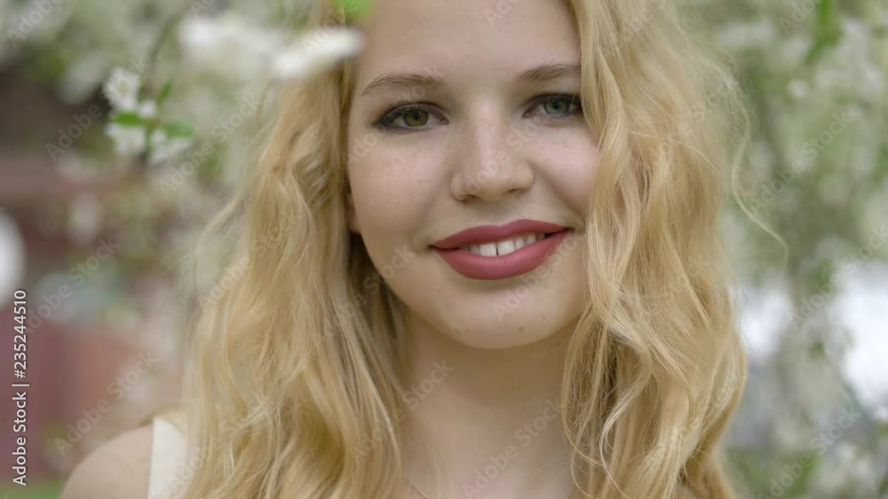 Beauty young blonde woman with multicolored eyes enjoying nature in spring city park, Happy Beautiful woman with blooming tree branch. Beauty young blonde woman with multicolored eyes enjoying nature in spring city park, Happy Beautiful woman with blooming tree branch.