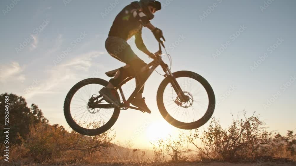 Cool mountain biker jumping at sunset, speeding up the trail, rushing down off road. Getting away from it all - activity, extreme Cool mountain biker jumping at sunset, speeding up the trail, rushing down off road. Getting away from it all - activity, extreme
