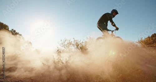 Montain biker-stuntman spectacularly stopping on road, with lot of dust blown by wind - extreme, fitness, getting away from it all photo