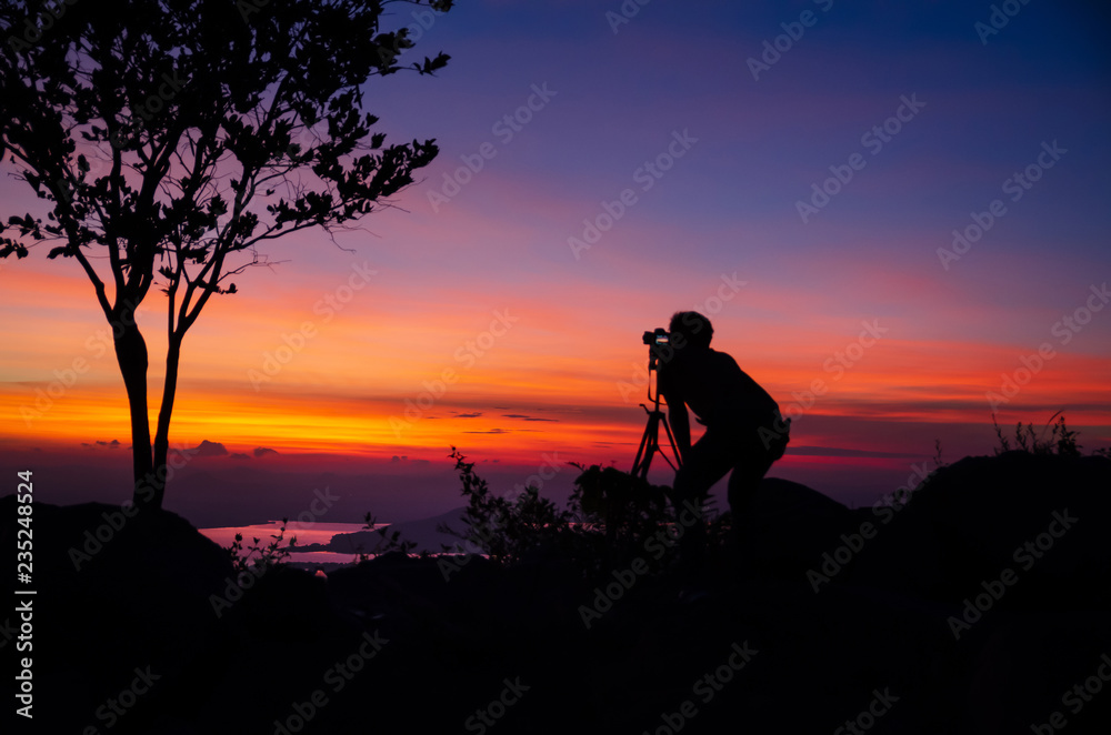 Silhouette Young man photographer taking nature photo on PhraYa Dern Thong mountain landscape.province Lopburi.Thailand. tourist photographe shooting dslr camera on tripod