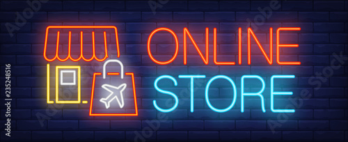 Online store neon sign. Glowing inscription with shop and paper duty free bag with plane emblem on brick wall background. Can be used for online shopping, advertisement, marketing