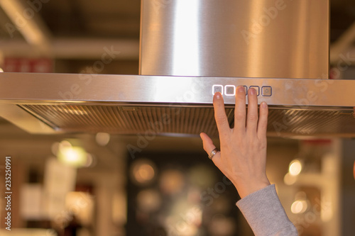 Hand touching the kitchen hood's buttons 