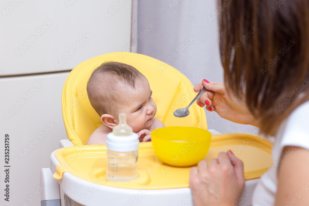 mother feeding her baby son with fruit puree mother feeding her baby son with fruit puree