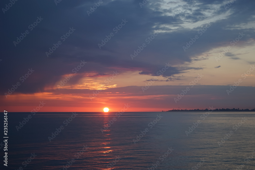 Amazing sunset on the ocean. View of dramatic cloudy sky and reflection of the sunlight on water.
