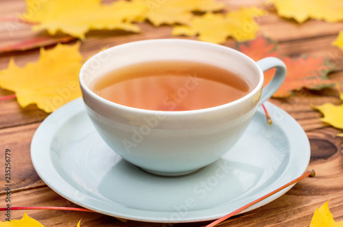 Cup of tea on the table with autumn leaves.