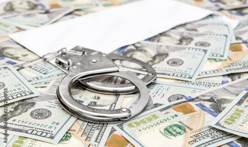 Handcuffs with envelope on background of dollar bills. Handcuffs with envelope on background of dollar bills.
