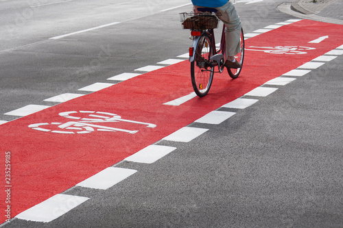 unrecognizable cyclist cycling and crossing street on red bike lane                               photo