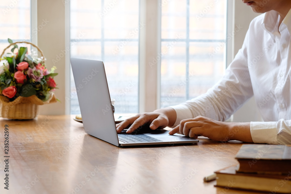 Cropped Man using laptop computer and books with coffee on office desk. Cropped Man using laptop computer and books with coffee on office desk.