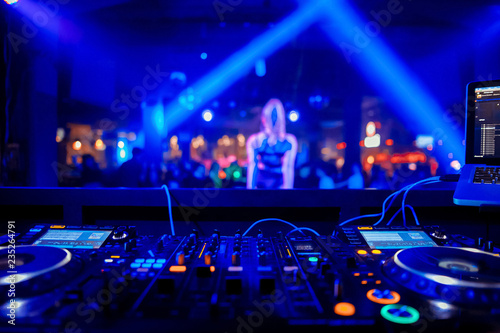 control DJ for mixing music with blurred people dancing at party in nightclub © Семен Саливанчук
