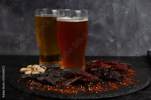 Assorted snacks, jerky on circle stone board with cold beer