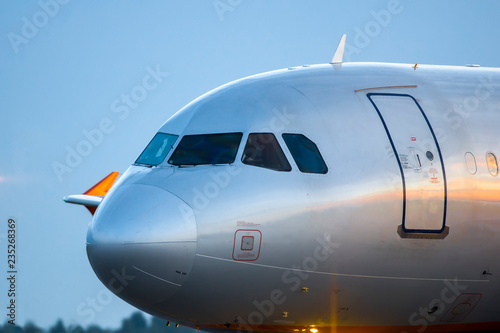 Modern civil airplane nose closeup view during sunrise.