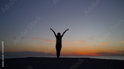 The girl is standing against the sunset and enjoying. girl stands on railing and raises her hands up against the background of city landscape in sunlight in evening. A naked woman enjoys life at the t