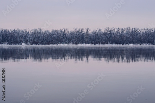 Winter landscape with river and forest. © J. Kearns