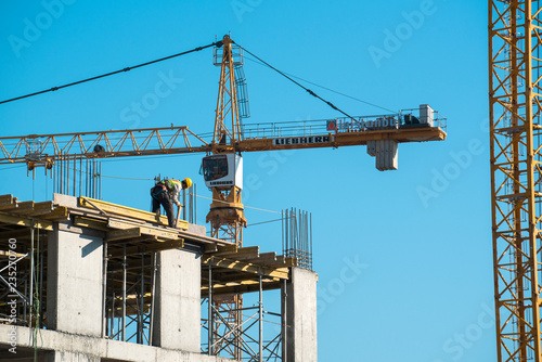 Construction worker works top of the building with crane background