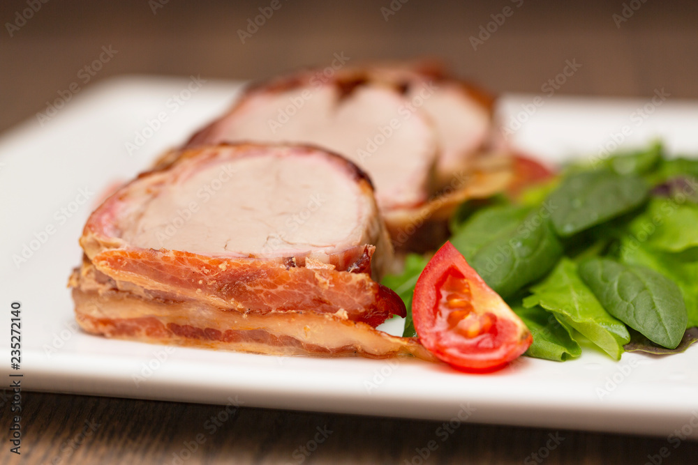 Roasted Pork Tenderloin Wrapped in bacon with lettuce and tomatoes Roasted Pork Tenderloin Wrapped in bacon with lettuce and tomatoes