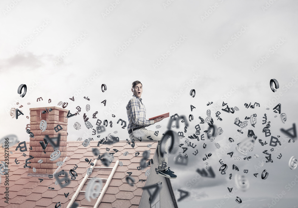 Fototapeta premium Man on brick roof reading book and symbols flying around