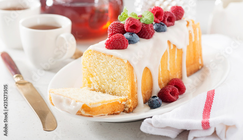 Butter vanilla cake for breakfast with glaze and fresh berries.
