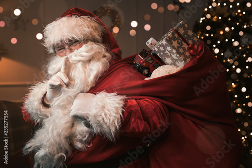 Santa Claus with finger on the lips gesturing shh sign 