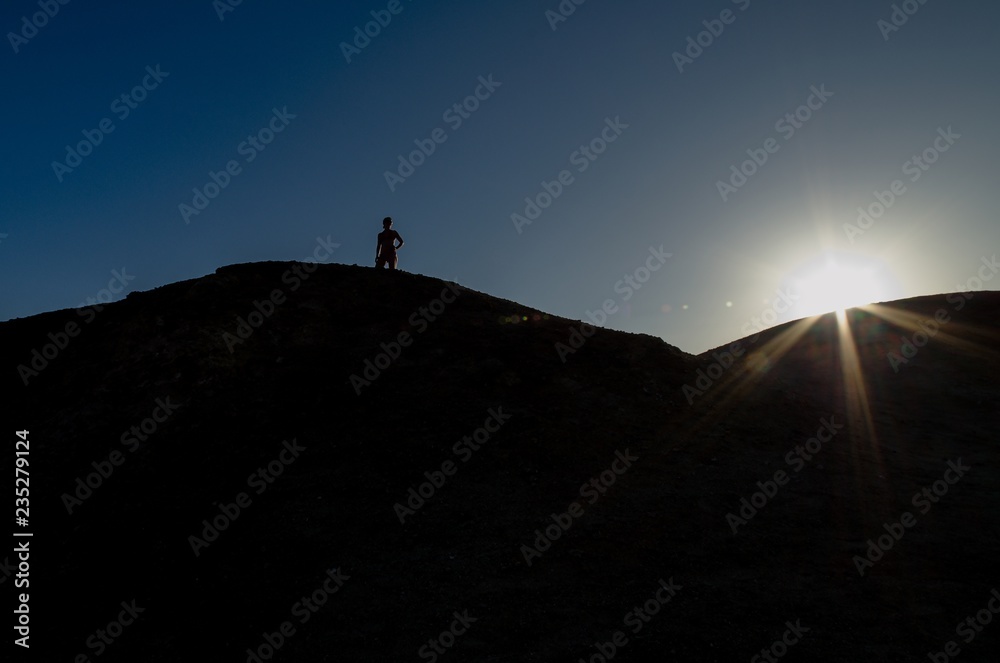 A woman looks up at the sand dunes.