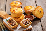 Traditional Australian Mini meat pies from shortbread dough on a wooden board over wooden background.