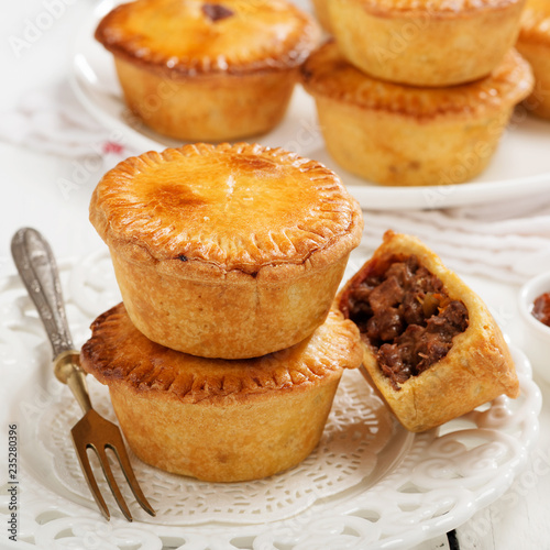 Traditional Australian Mini meat pies from shortbread dough on a white wooden background.