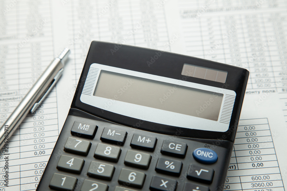 Calculator on the table with paper tables and pen Calculator on the table with paper tables and pen