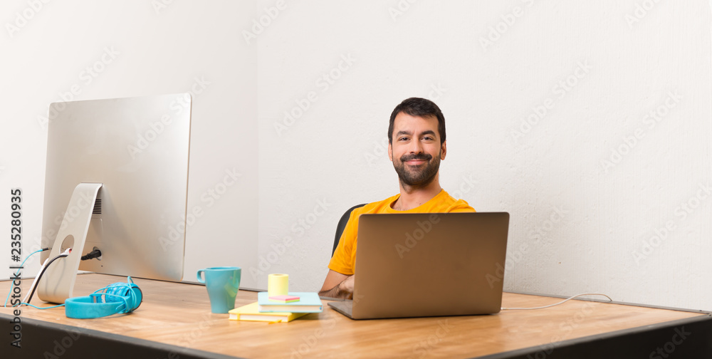 Man working with laptot in a office keeping the arms crossed in lateral position while smiling