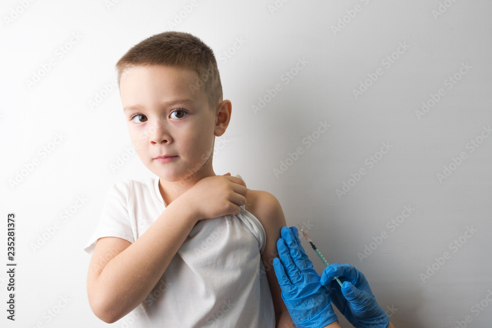 Young boy wants to do medical injection. Not afraid of vaccination. Boy and a doctor with a syringe in his hands in blue gloves. Vaccination concept, preventional immunization. Young boy wants to do medical injection. Not afraid of vaccination. Boy and a doctor with a syringe in his hands in blue gloves. Vaccination concept, preventional immunization.