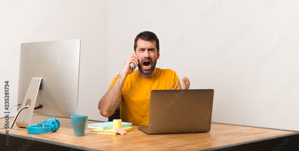 Man working with laptot in a office talking to mobile Man working with laptot in a office talking to mobile