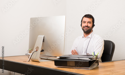 Telemarketer man in a office keeping the arms crossed in frontal position